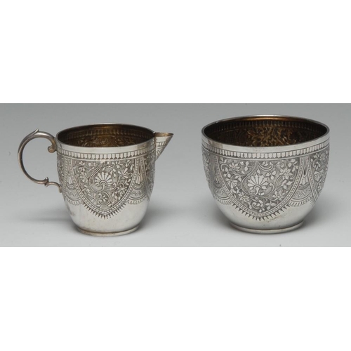 605 - A Victorian silver cream jug and sugar basin, each chased with dense scrolling foliage, gilt interio... 