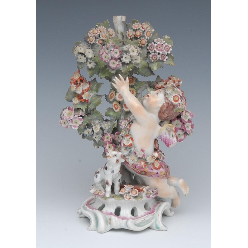 73 - A Bow figure, Cupid, the winged putto kneeling and reaching up into flowering bocage with a lamb bes... 