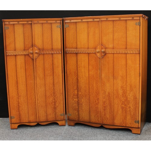 223 - A mid 20th century oak veneered bedroom suite, comprising two double wardrobes and a dressing table ... 