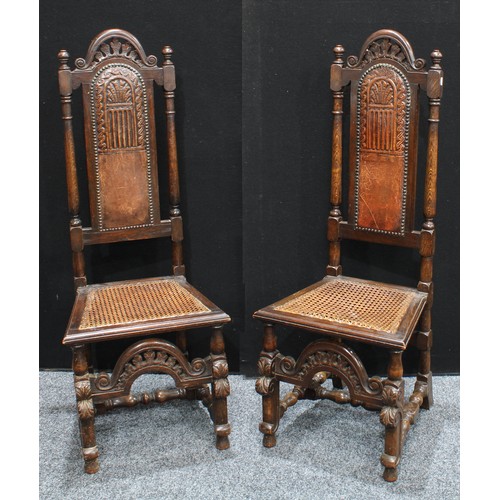 224 - A set of four oak dining chairs, of Spanish baroque design, each tall arced back crested by pierced ... 