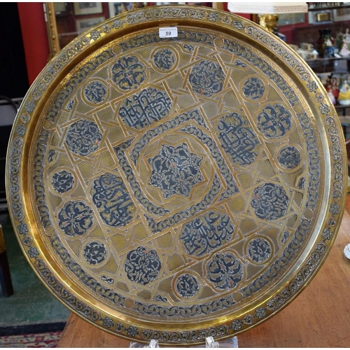 59 - An Islamic brass table top tray, inlaid with copper and white metal, 69cm diameter