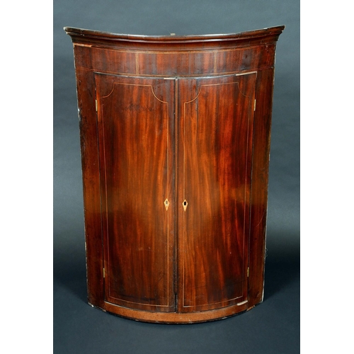 1235 - A George IV mahogany bow-fronted wall hanging corner cupboard, outswept cornice above a deep frieze ... 