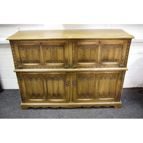 325 - A substantial Old charm oak stereo cabinet, hinged to above two linen fold panelled fall front and t... 