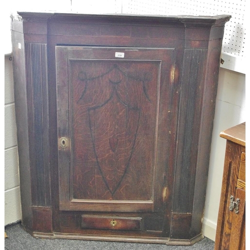 339 - A George III oak corner cupboard, inlaid ebony shield shaped border, enclosing four shaped shelves a... 