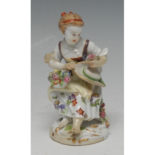 370 - A 19th century Meissen figure, of a flower girl, seated on an upturned basket with a basket of flowe... 