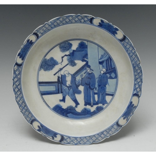 414 - A 19th century Chinese porcelain shaped circular dish, painted in underglaze blue with robed elders ... 