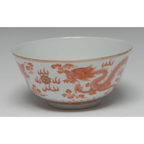 420 - A Chinese bowl, decorated in red with dragons chasing the flaming pearl, banded with breaking waves,... 