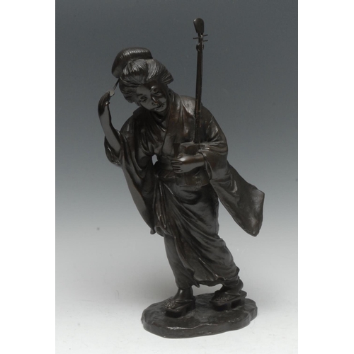 509 - Japanese School (Meiji period), a dark patinated bronze, of a geisha holding a shamisen, shaped oval... 