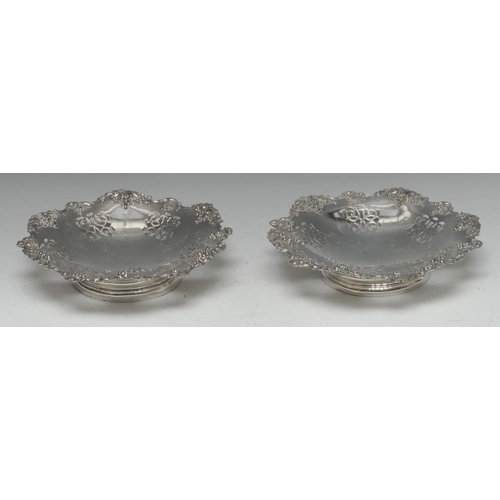 522 - A pair of early 20th century E.P.N.S shaped circular dishes or coasters, each pierced and applied wi... 