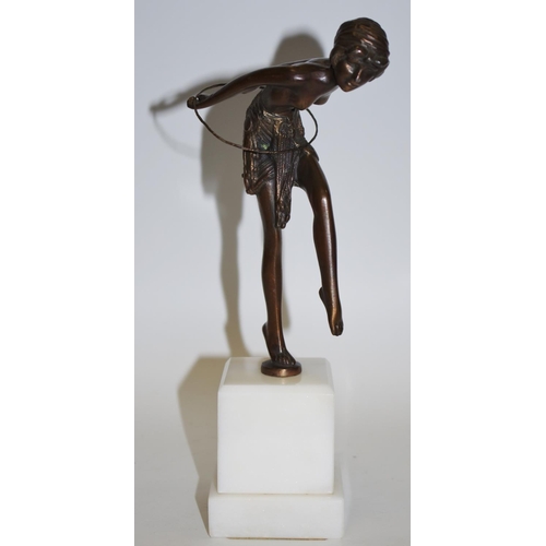 50 - A bronzed figure of a dancing girl with hula hoop, white plinth base.