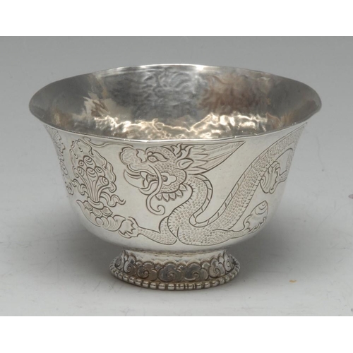 576 - A Chinese/Thai silver flared circular libation bowl, chased with ferocious dragons, the spreading fo... 