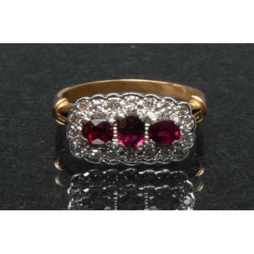 844A - A ruby and diamond cluster ring, central row of three oval deep red rubies, surrounded by a band of ... 