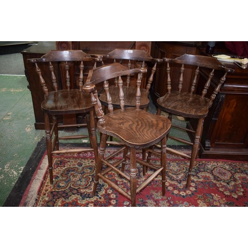 510 - A set of four elm bar stools, each with a curved cresting rail, turned spindles, saddle seat, turned... 