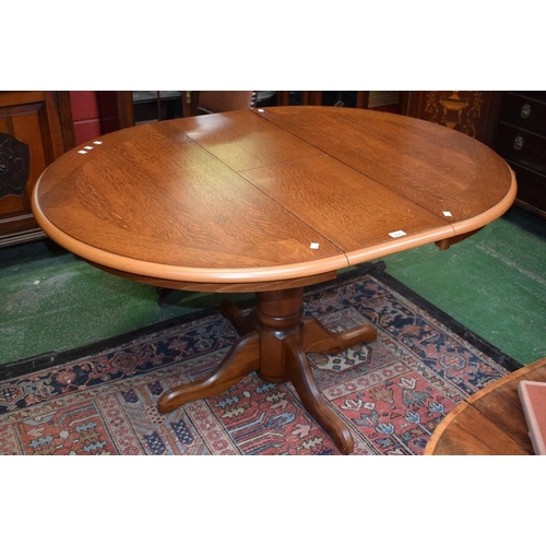 567 - A contemporary oak circular extending dining table, fold-out central leaf, turned column, quadform b... 