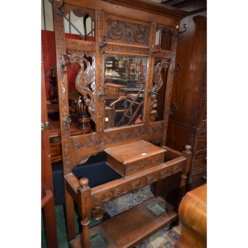 629 - A 20th century carved oak hallstand, outswept cornice above a central bevelled plate mirror, an arra... 