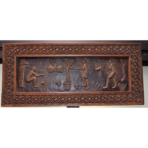 130 - Tribal Art - an African embossed copper plaque, Village Life, carved frame, possibly Zambian