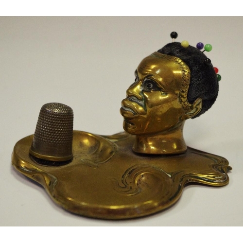 244 - An Art Nouveau brass novelty pin cushion and thimble stand, as the head of a black woman, the base s... 