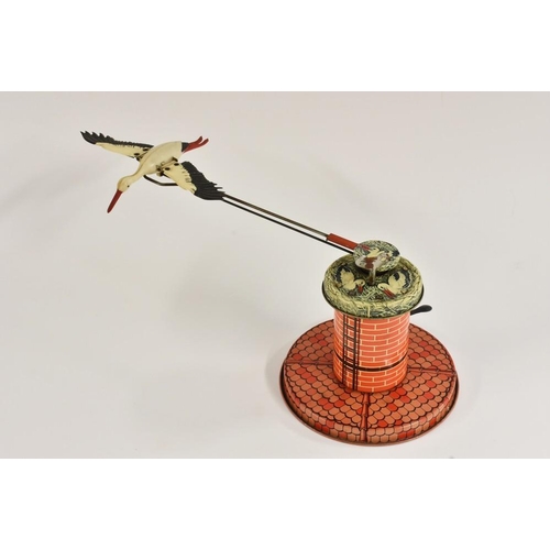 148 - A West German tinplate Adebar Stork, windup toy, THE stork flies around a central base and flaps win... 