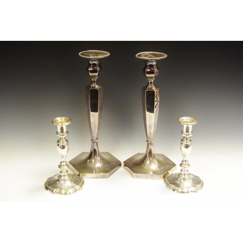 317 - A pair of silver plated candlesticks. tapering hexagonal columns, on plinth base; another pair of sm... 