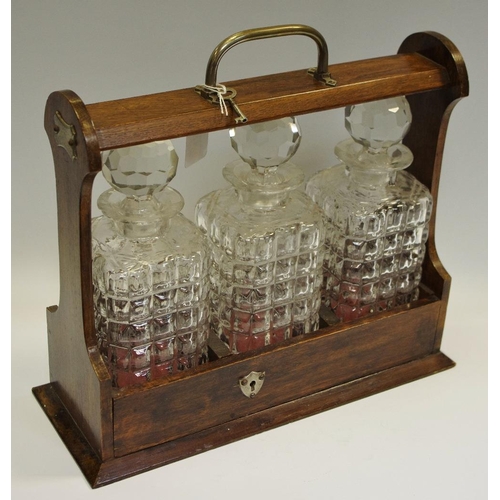 16 - An Edwardian oak three-bottle tantalus, with key, c.1905