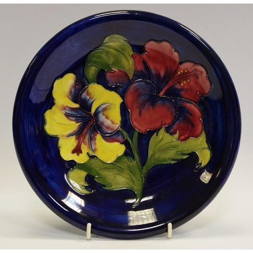 7 - A Moorcroft Hibiscus pattern circular plate, tube lined with large red and yellow flowerheads, on a ... 