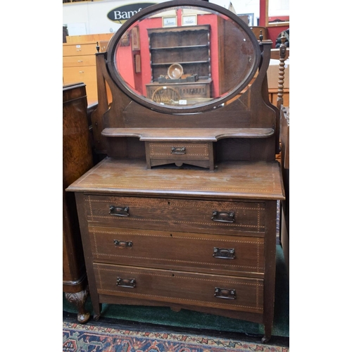 151 - An Edwardian style oak dressing table, the shaped superstructure with an oval bevelled plate mirror ... 