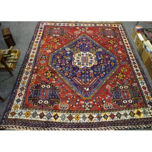 158 - A Hand Woven Persian Qashqai Rug, geometric patterns in burnt sienna, cobalt and brown on a red grou... 