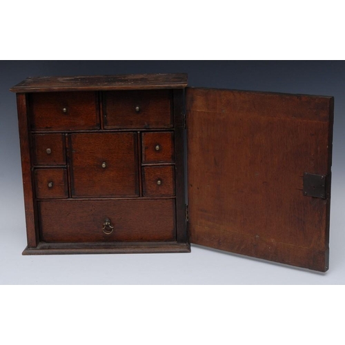 1250 - A Queen Anne walnut spice cupboard, shallow cornice above a rectangular crossbanded door with book-m... 