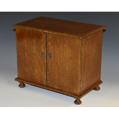 1285 - An early 20th century oak table cabinet, hinged top above a pair of rectangular doors, enclosing a j... 