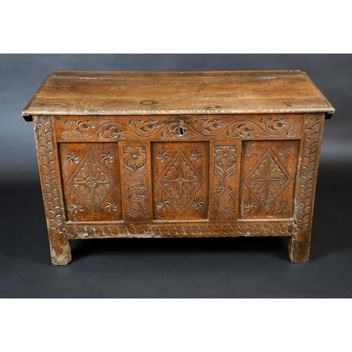 1304 - An early 18th century oak blanket chest, hinged rectangular top, three panel front carved with lozen... 