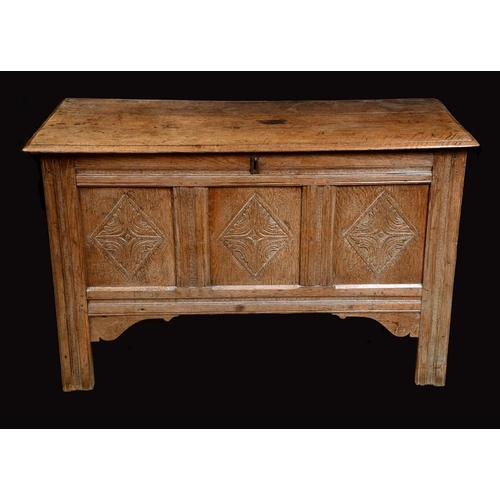 1305 - An early 18th century blanket chest, hinged moulded top, three panel front carved with lozenges, sti... 