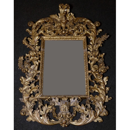 1332 - An 18th century Baroque giltwood and gesso looking-glass, crested by an eagle and boldly carved with... 