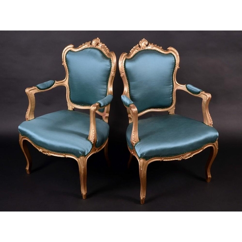 1445 - A pair of Louis XV style giltwood fauteuils, cartouche shaped backs, scroll arms, stuffed over uphol... 