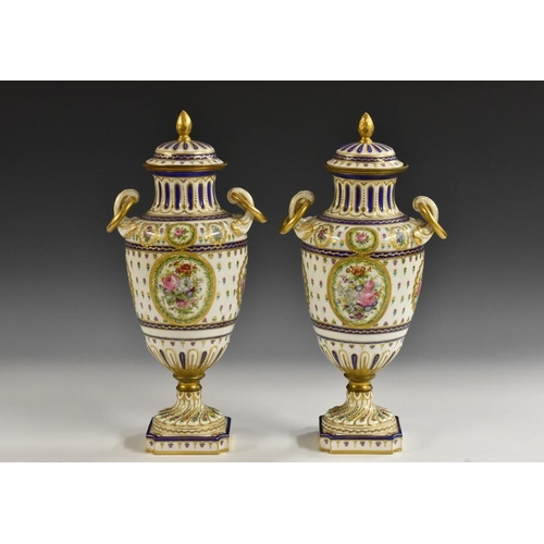 258 - A pair of Continental pedestal two handled vases, in the Sevres style, painted with spring flowers w... 