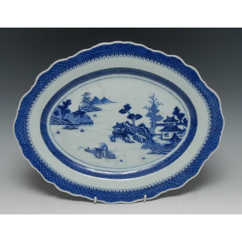 344 - A Chinese shaped oval serving plate, decorated in underglaze blue with pagodas, sampan and rockwork,... 