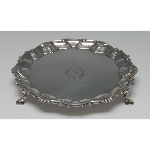 499 - A George II silver shaped circular waiter, fluted shell and C and S-scroll border, hoof feet, creste... 