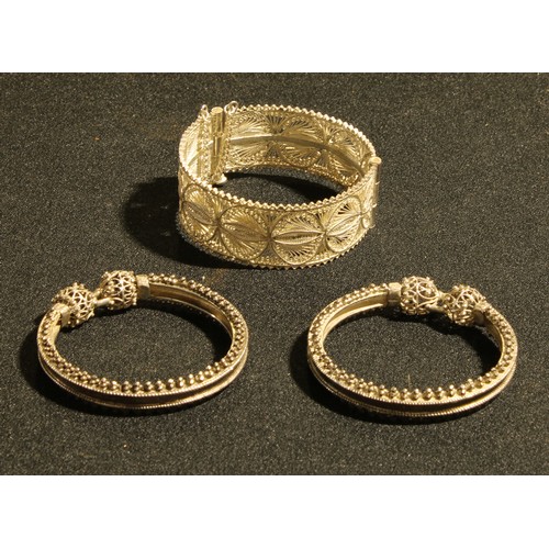 548 - A white metal filigree bangle; another pair of white metal bangles (3)