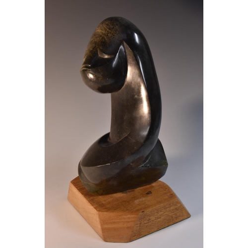 3080 - A hardstone desk sculpture, carved as an abstract female head, mounted to rotate, hardwood base, 31.... 