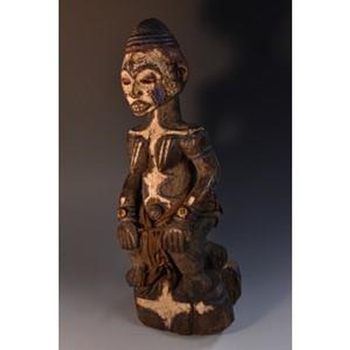 3520 - Tribal Art - an African power figure, seated on a stool, decorated in coloured pigments and wearing ... 