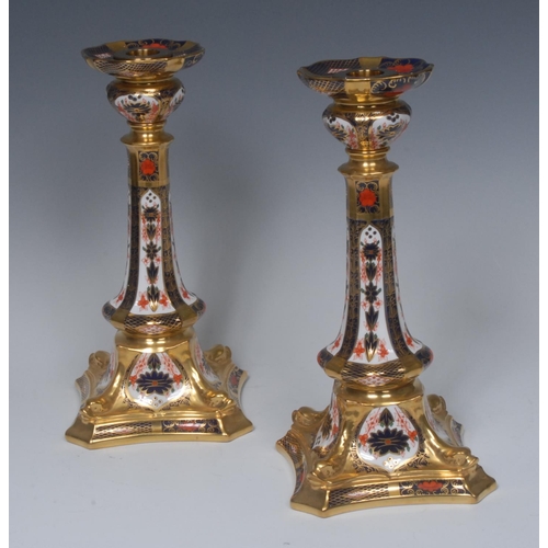 109 - A pair of Royal Crown Derby 1128 pattern Castleton candlesticks, dolphins to angles, incurved square... 