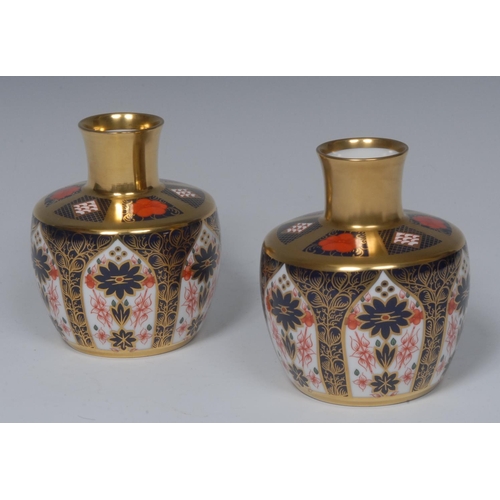 111 - A pair of Royal Crown Derby 1128 pattern bottle vases, solid gold bands, printed marks, boxed