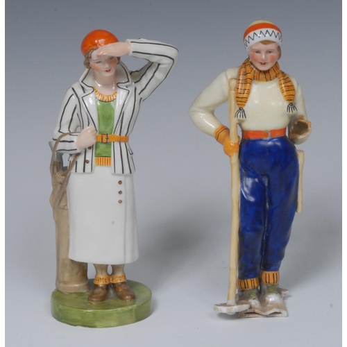 129 - A Royal Crown Derby figure, Lady Golfer, she stands wearing an orange berry and striped jacket, hold... 