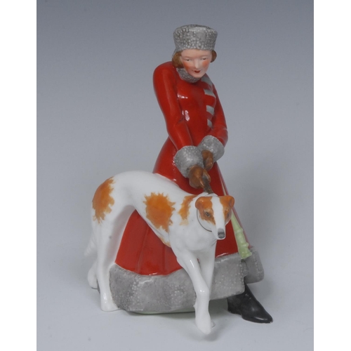 131 - A Royal Crown Derby figure, Olga, she stands, wearing a fur trimmed red trench coat holding a Borzoi... 