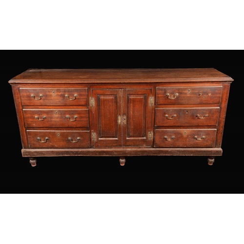 1573 - A George III oak low dresser, moulded top above a pair of rectangular raised and fielded panelled do... 