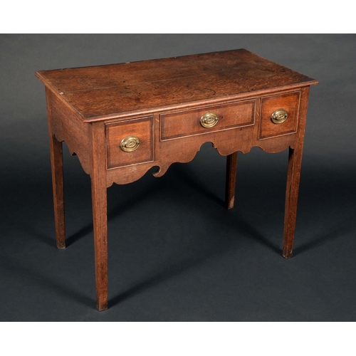 1575 - A George III oak lowboy, moulded oversailing top above a central short drawer and flanked by a furth... 