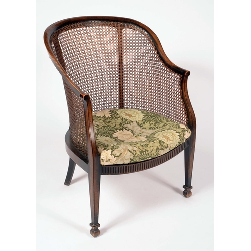 1580 - A George III Revival bergere library chair, downswept arms terminating in scrolls, reeded frieze, ta... 