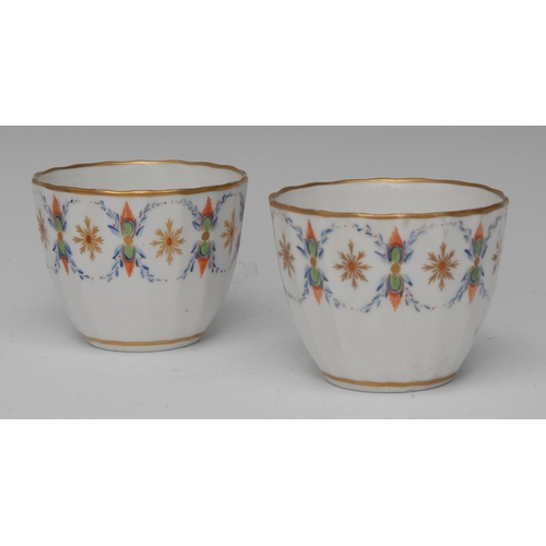 159 - A pair of Pinxton Bute shaped fluted tea bowls, painted with bursting stars in red and gilt within b... 