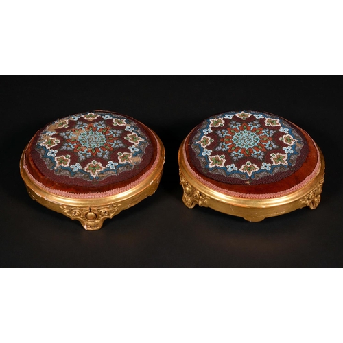 1611 - A pair of Victorian giltwood and gesso circular footstools, stuffed-over beadwork tops, outswept fee... 