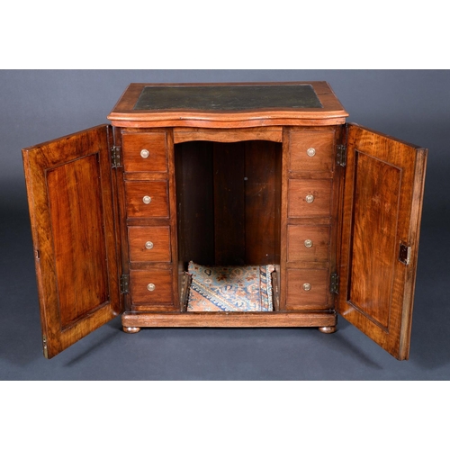 1658 - A Victorian walnut 'office cabinet', serpentine top with inset leather writing surface above a pair ... 