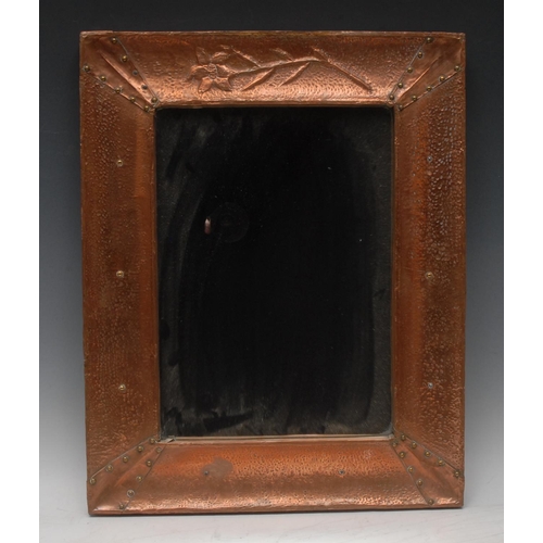 1676 - An Arts and Crafts copper rectangular looking-glass, crested by a singular flower, planished through... 